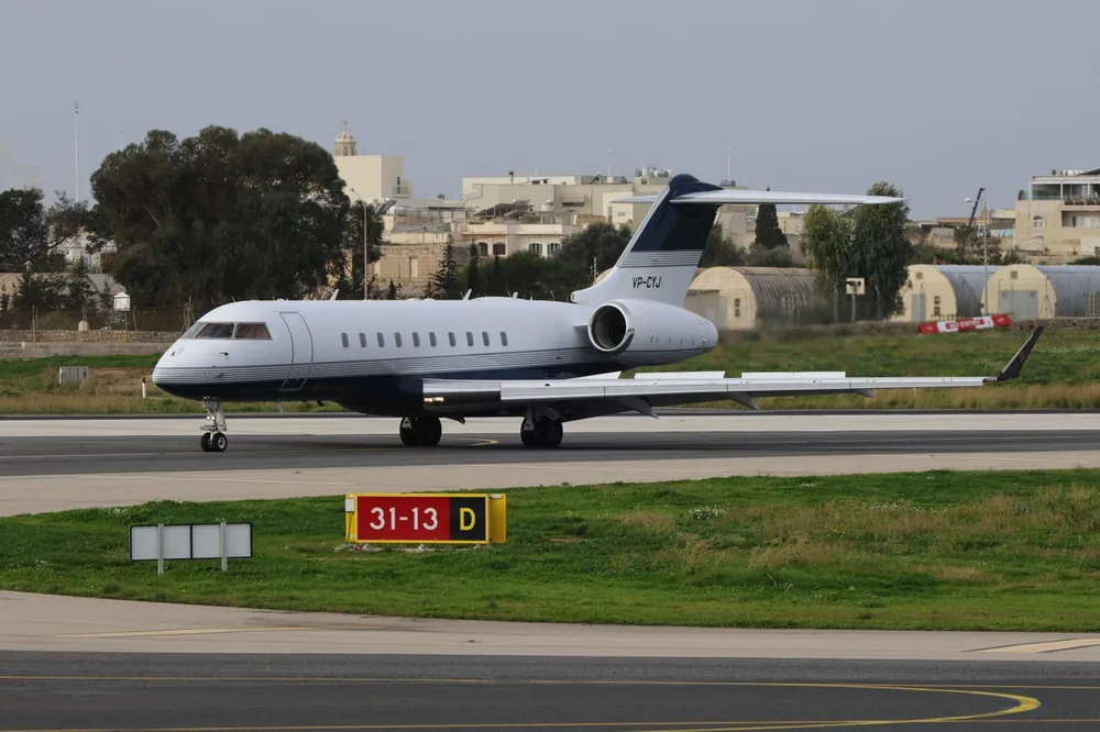White business aircraft taxiing past airport buildings