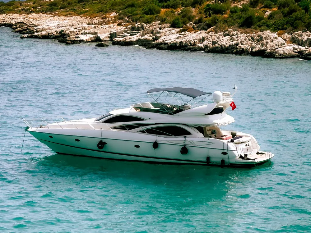 White motor yacht beside a rocky shoreline